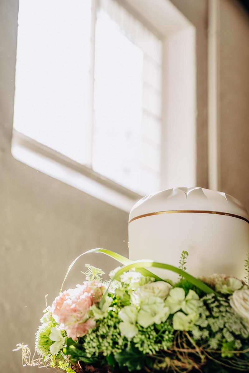Urne mit Blumenschmuck am Fenster